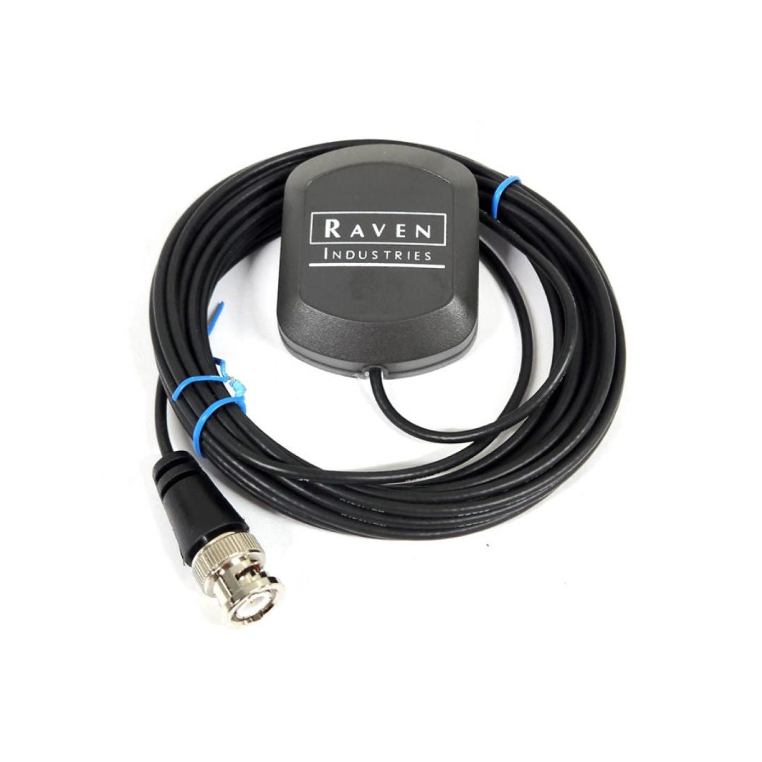 The Raven Patch Antenna - Compact GPS Guidance Relay (063-0172-101) from Raven, equipped with a black cable and connector and a gray device marked "Raven Industries," guarantees high-performance GPS reception. This setup delivers precision GPS guidance for unmatched accuracy and reliability in challenging environments.