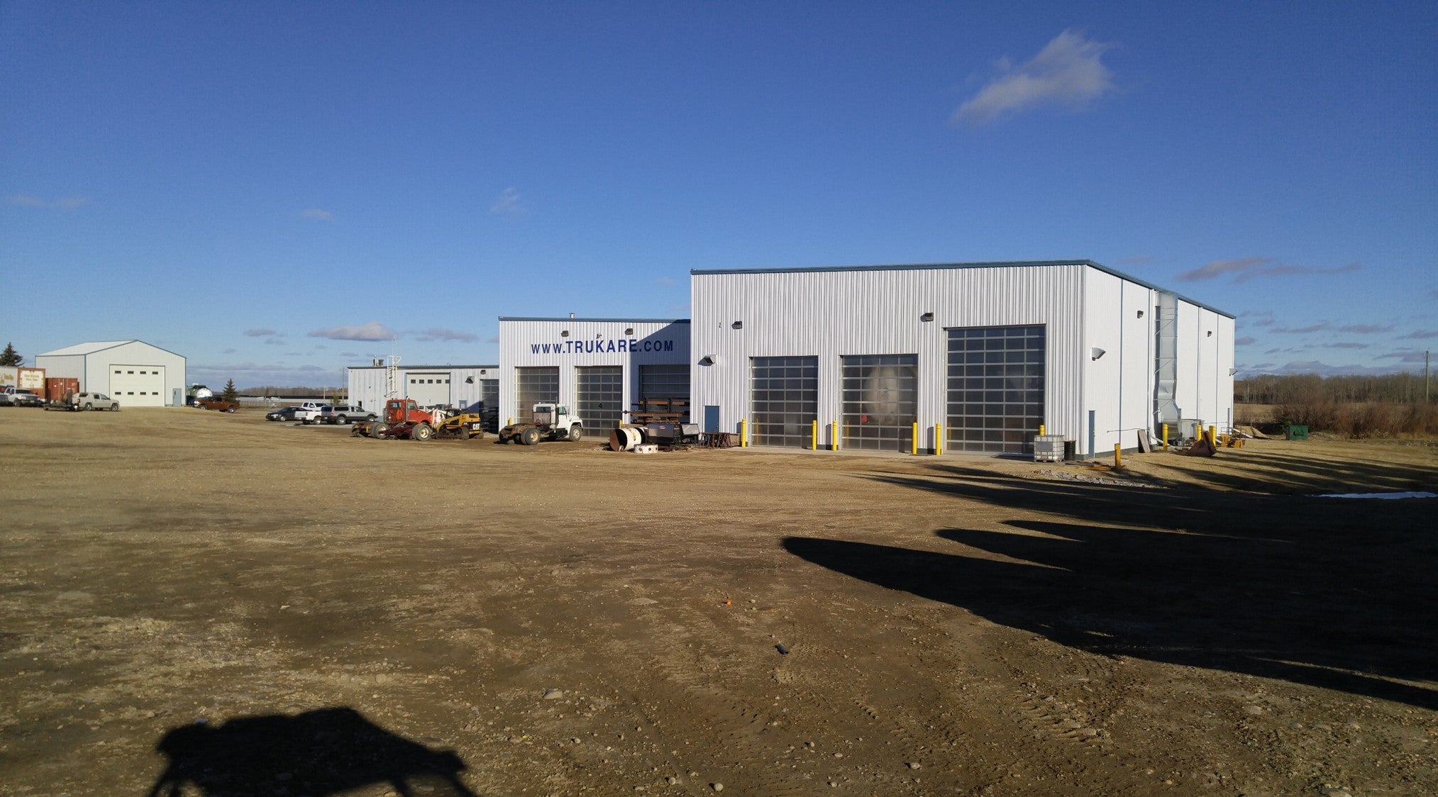 A large industrial building in Alberta, emblazoned with a sign reading "www.trukare.com," is surrounded by vehicles on a clear day, specializing in pressure vessel services and equipment service and repair.
