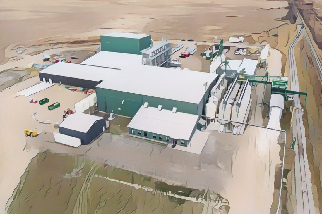 Aerial view of an industrial facility in a prairie landscape, with several green-roofed buildings and machinery.