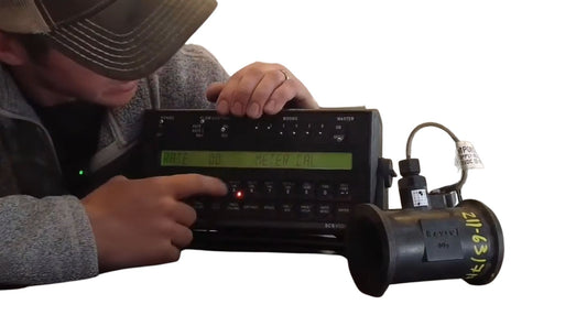 Man calibrating a flow meter device with an electronic control panel.