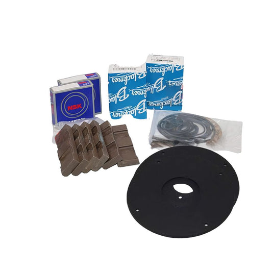 Collection of automotive or mechanical components including brake pads, bearing boxes labeled "NSK" and "Rotomac," a set of gaskets or seals, and a large black circular gasket with a central hole and smaller mounting holes.
